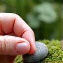 Hands working on arranging small rocks in a miniature zen garden during a workshop